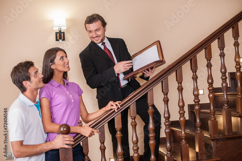Estate agent with young couple on ladder.
