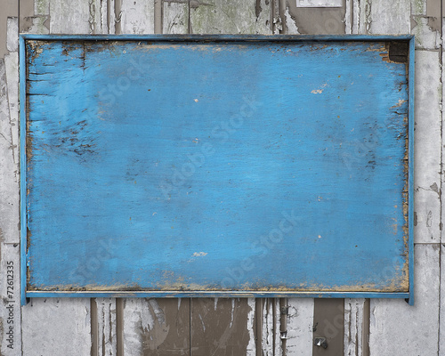 old blue blank weathered wood noticeboard on rough dirty wall