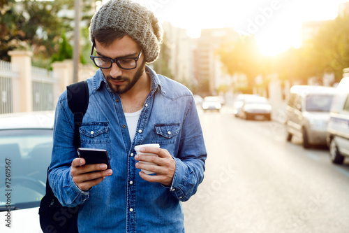Modern young man with mobile phone in the street. photo