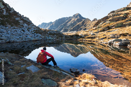 Male hiker takes a rest sitting next a mountain lake photo