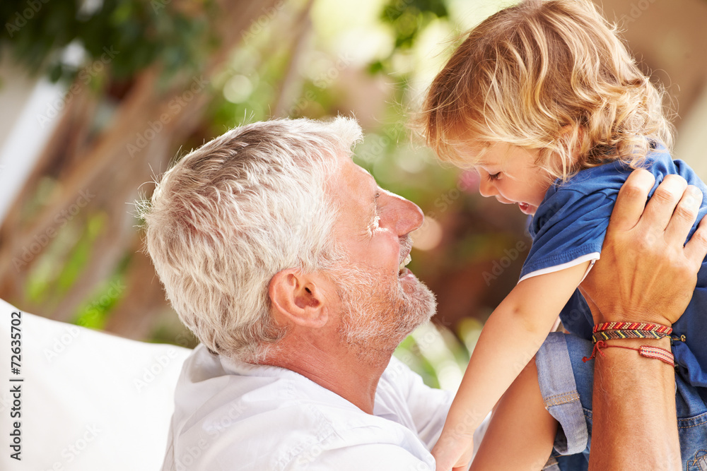 Grandfather At Home Playing With Grandson In Garden