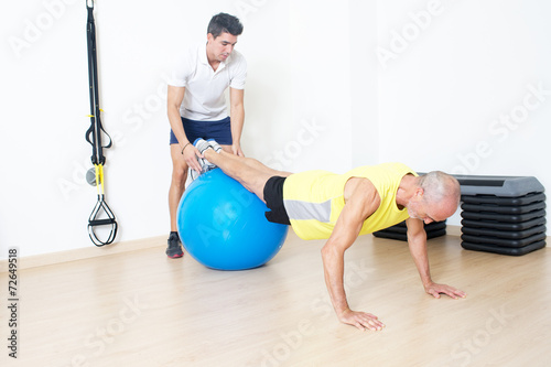 Senior beim Suspension Training mit Trainer photo