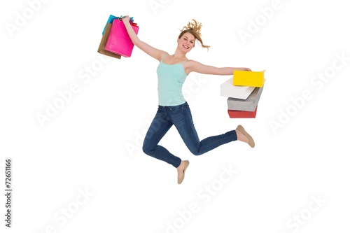 Excited blonde jumping while holding shopping bags