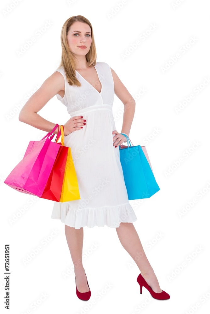 Happy blonde holding shopping bags in white dress