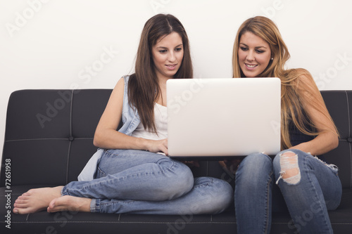 two women using laptop on sofa in her home