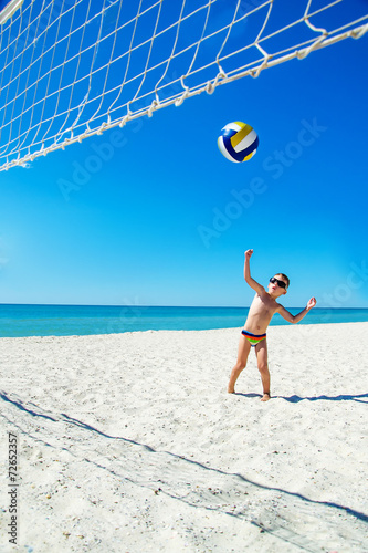 Kid play volleyball on sea beach