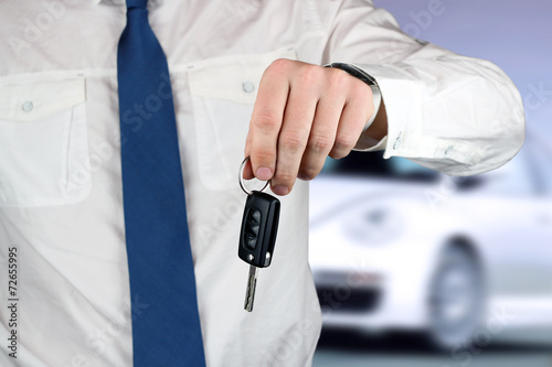 Young successful businessman offering a car key. Close-up of dri