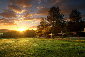Fototapete Pantone 2025 Mocha Mousse Malerische Landschaft, eingezäunte Ranch bei Sonnenaufgang  © Zsolnai Gergely