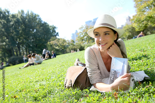 Cheerful woman in Central Park reading New York city guide