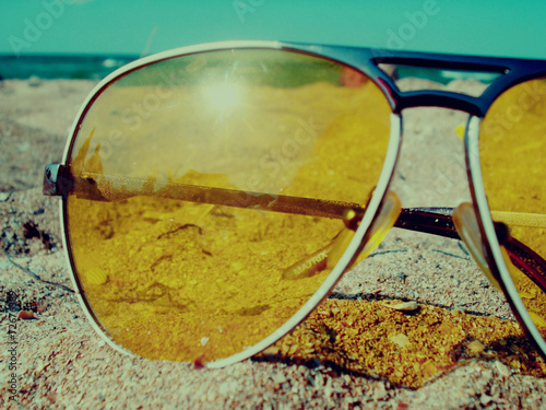 sunglasses on sand near a sea