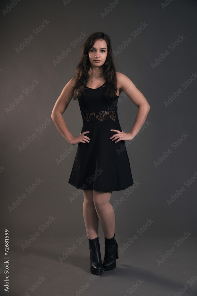 Cute brunette teenage girl wearing black dress. Studio fashion s
