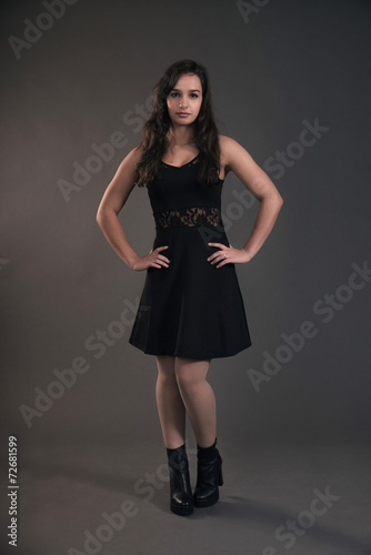 Cute brunette teenage girl wearing black dress. Studio fashion s