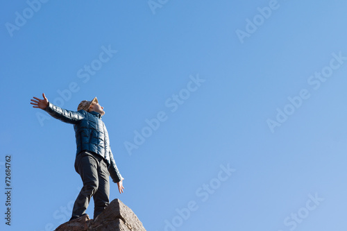 Exuberant young man on top of an old stone wall