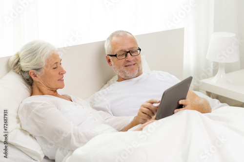 happy senior couple with tablet pc at home
