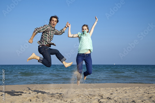 Pareja de novios saltando en la playa de forma divertida