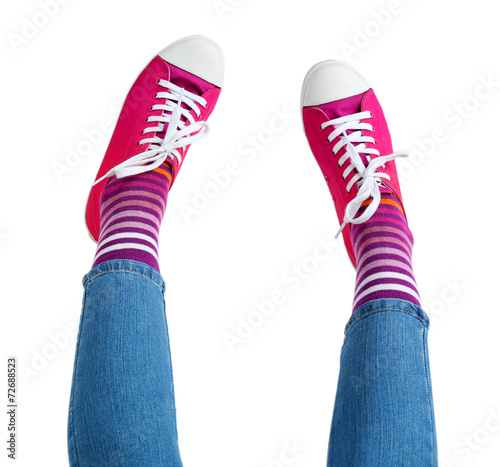 Female legs in colorful socks and sneakers isolated on white