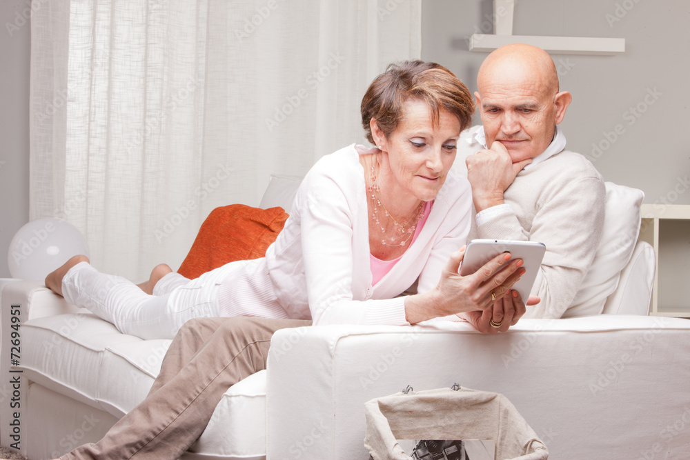 mature couple reading news in digital devices mature couple reading news in digital devices
