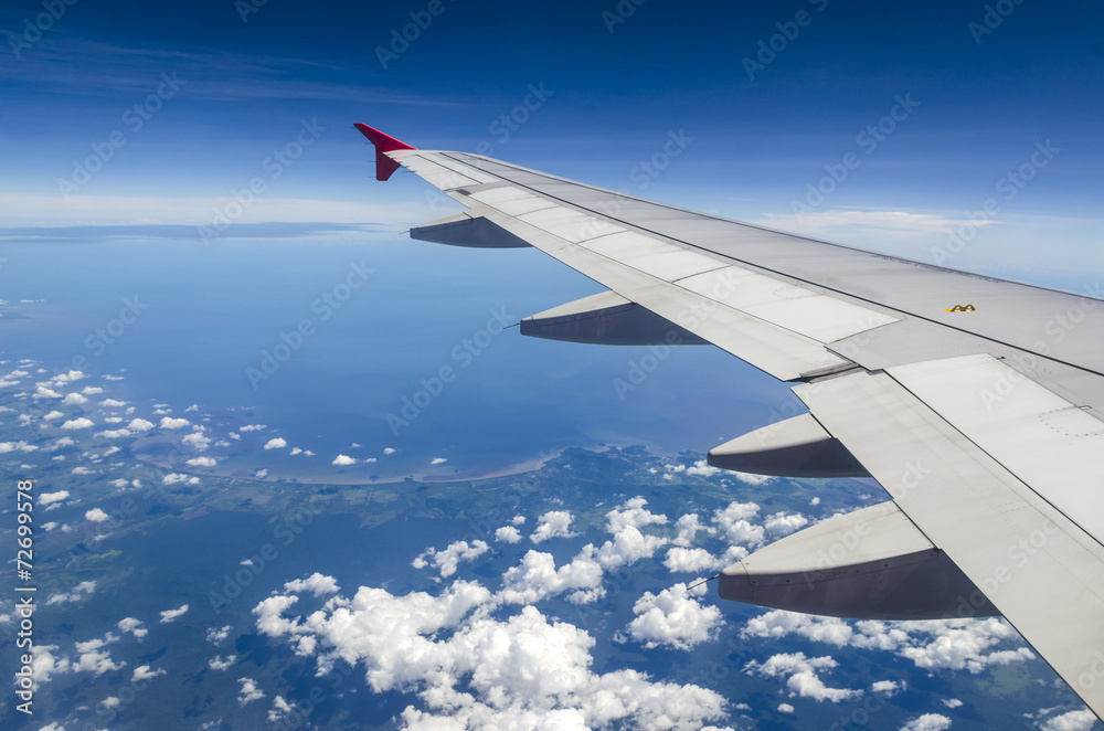 Wing of airplane flying above the clouds in the sky Wing of airplane flying above the clouds in the sky