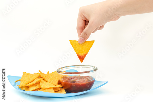 Dipping tortilla chips with salsa sauce in dish on white backgro