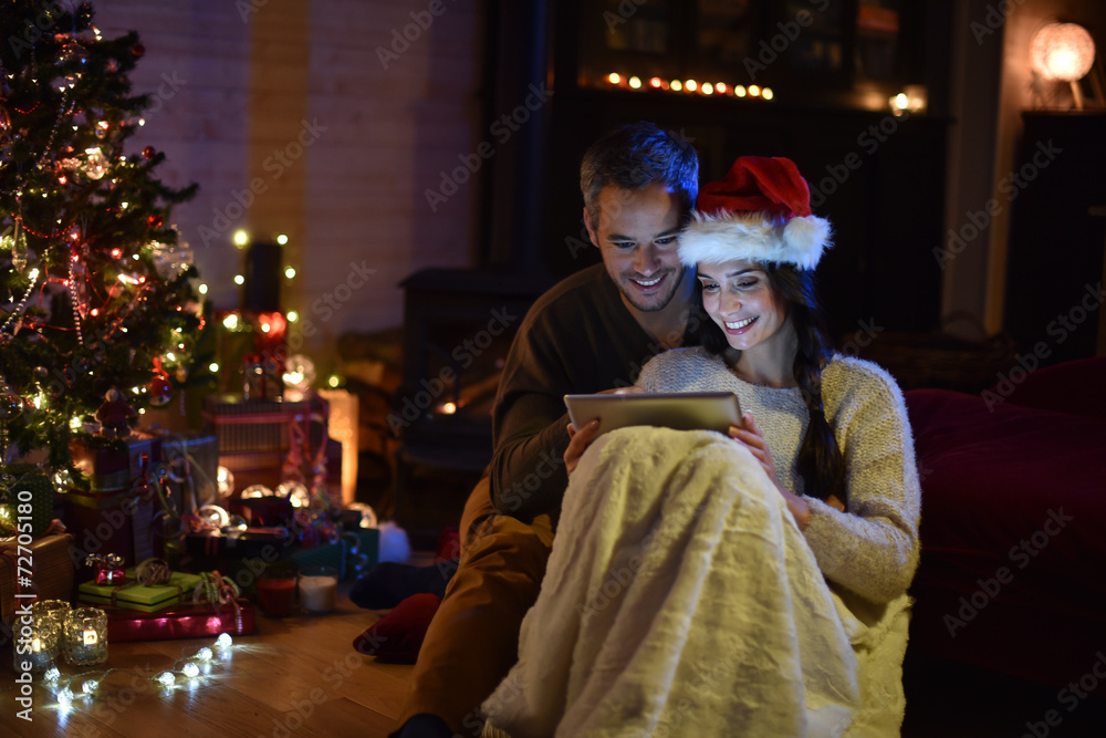 Romantic couple sharing a digital tablet near a wood stove on a