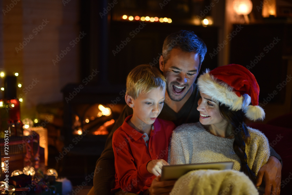 lovely family sharing a digital tablet near the wood stove on a