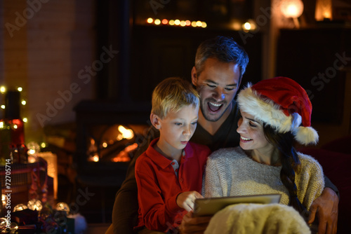 lovely family sharing a digital tablet near the wood stove on a © jackfrog