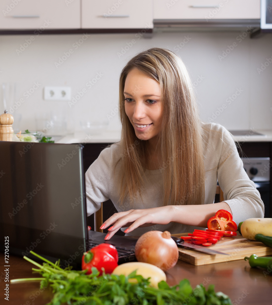  woman using notebook while cooking lunch