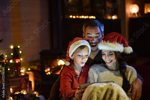 lovely family sharing digital tablet near the wood stove on a wi