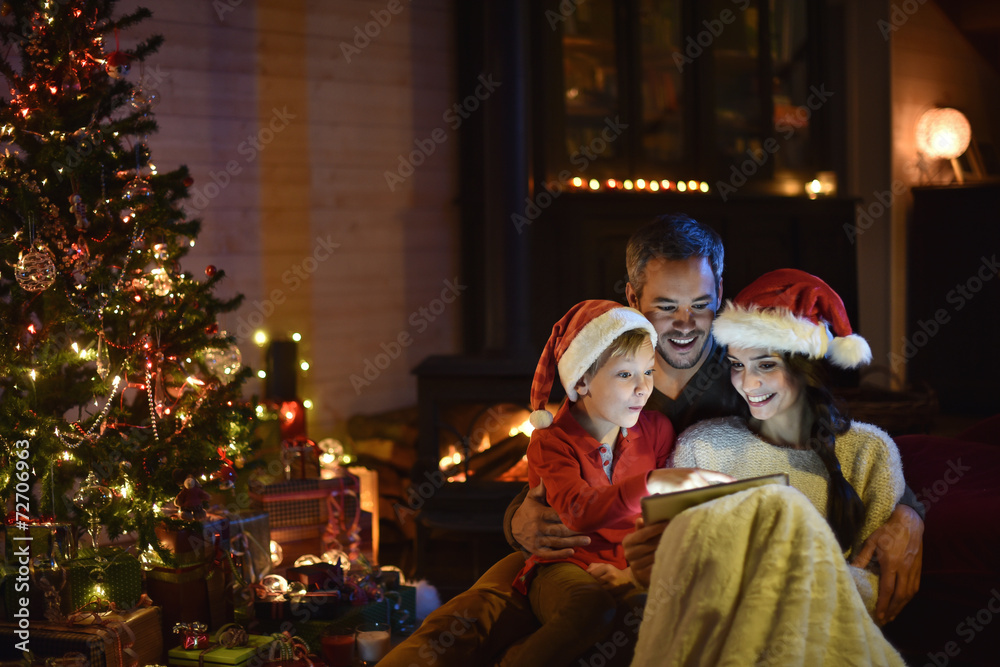 lovely family sharing digital tablet near the wood stove on a wi