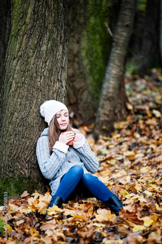 Girl sitting under the tree with a cup in her hands