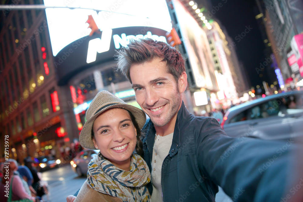 Couple standing in Time Square quarter by night