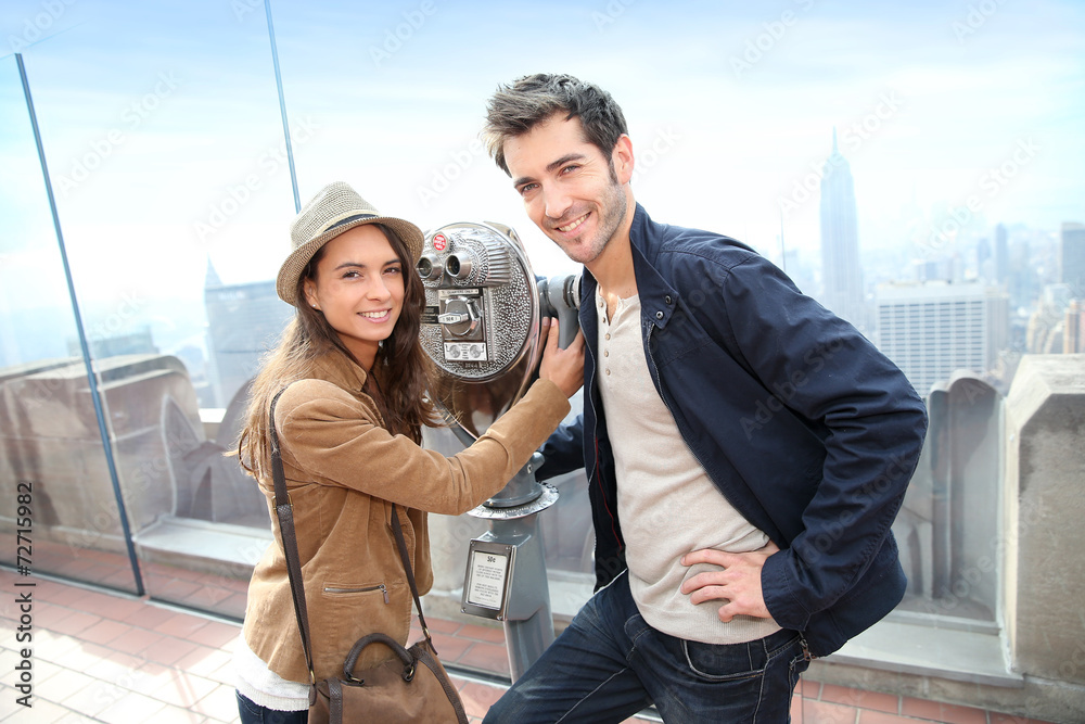 Tourists looking through telescope on Top of the Rock building Tourists looking through telescope on Top of the Rock building