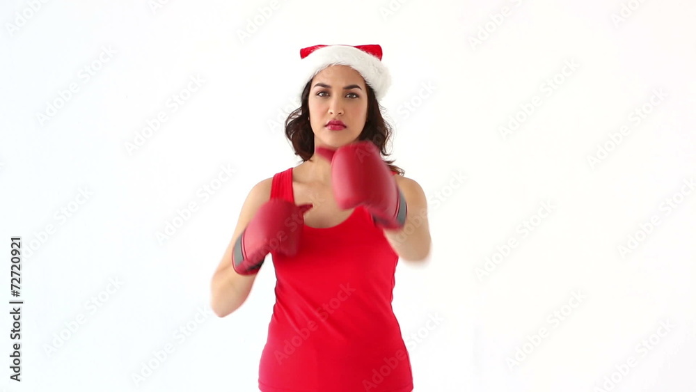 Fit festive brunette punching with boxing gloves in santa hat Fit festive brunette punching with boxing gloves in santa hat