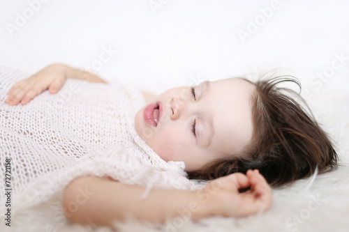 portrait of 2 years child sleeping on white fur plaid
