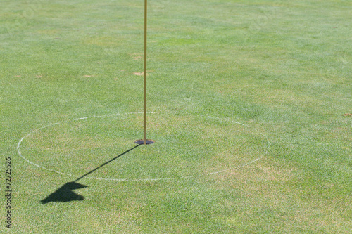 golf hole on green grass with shadow flag