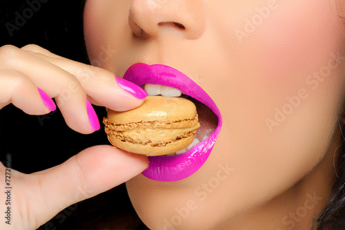 Close up to Macaroon on hand , beautiful caucasian woman eating photo