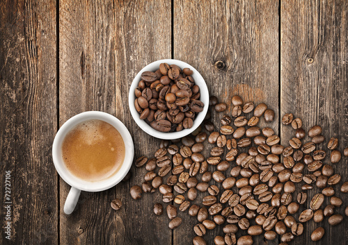 Coffee cups full of fresh espresso and beans on wooden table