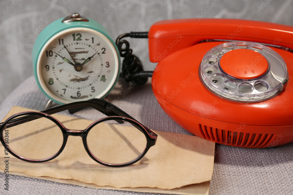 Fototapeta premium Retro phone, clock and glasses on table in room