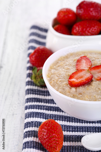 Tasty oatmeal with strawberry on table close-up