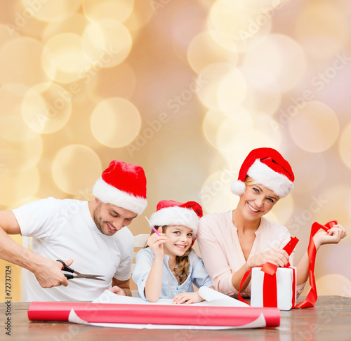 happy family in santa helper hats packing gift