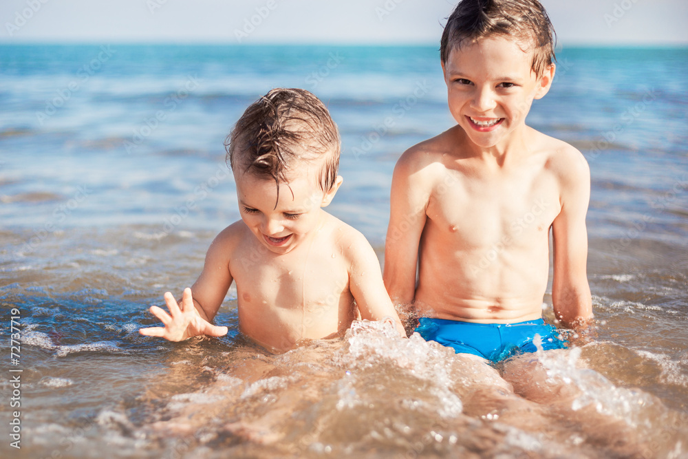 smiling boys sitting on beach smiling boys sitting on beach