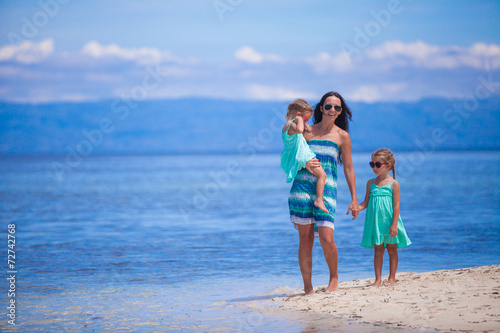 Adorable little girls and young mother on tropical white beach