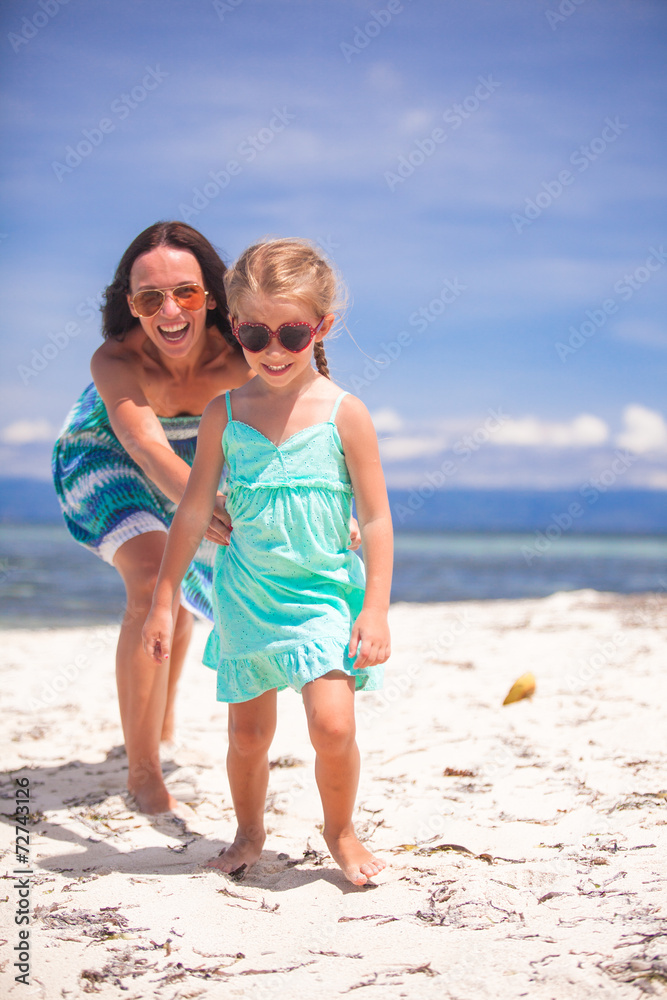 Little girl and young mother having fun on tropical beach