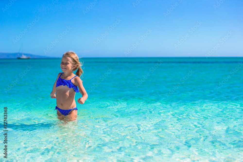 Adorable little girl have fun in shallow water at tropical beach Adorable little girl have fun in shallow water at tropical beach