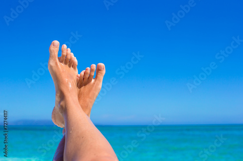 Closeup of female legs background of the turquoise sea © travnikovstudio