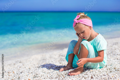 Little adorable girl with cell phone during beach vacation