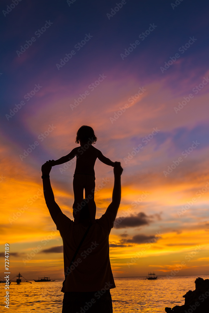 silhouettes of father and child on sunset sea background