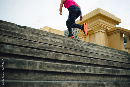 Female urban jogger running up stairs