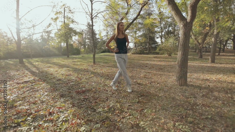 The camera shoots sports girl during doing exercises in the park The camera shoots sports girl during doing exercises in the park