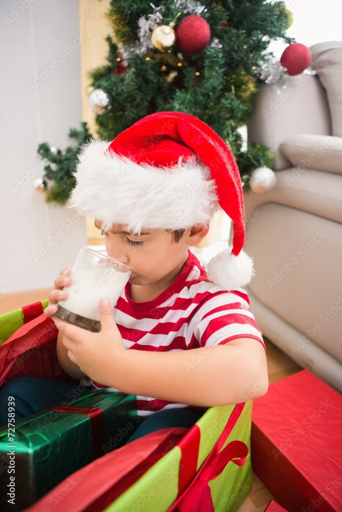 Cute boy in large christmas present drinking milk